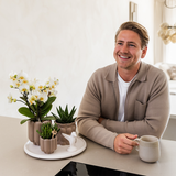 Kolibri Orchids | Geschenkset Slow Living | Grüne Pflanzen mit weißen Phalaenopsis Orchideen Lausanne in beigefarbenen Keramikübertöpfen auf weißem Tablett